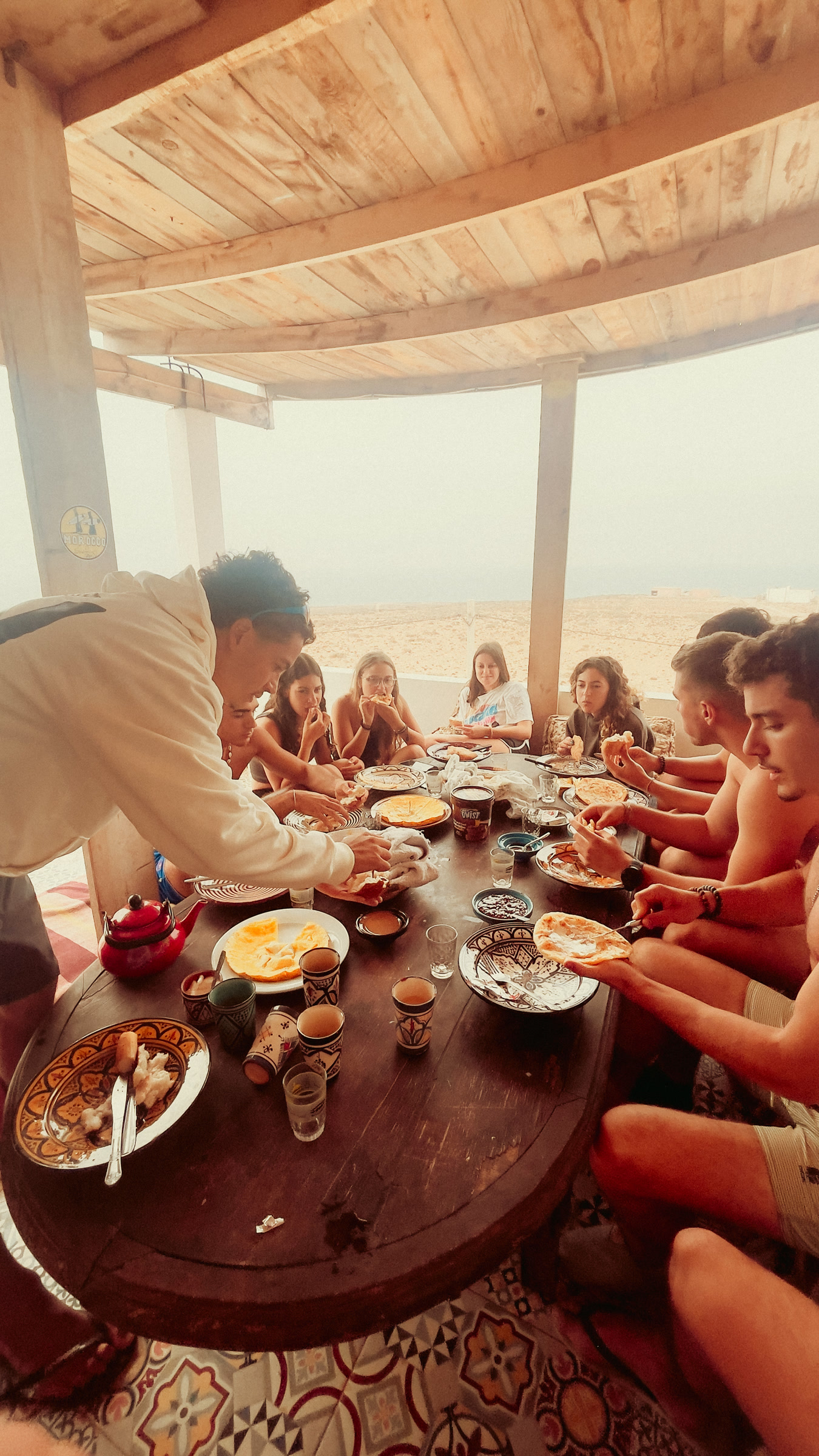 Grupo toma o pequeno-almoço numa mesa comprida