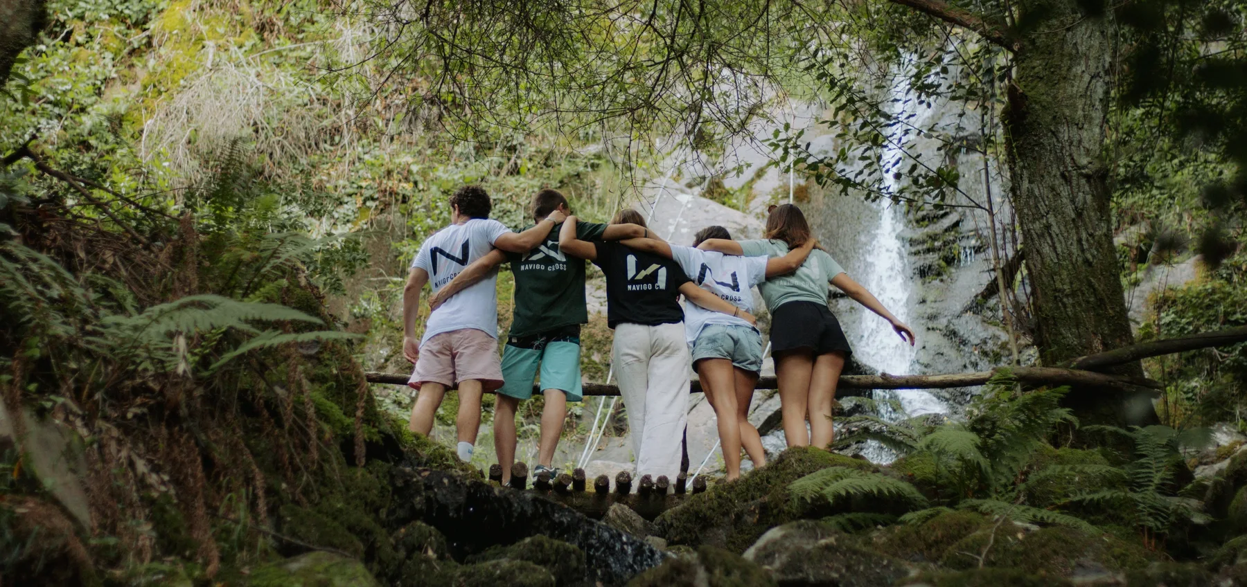 Amigos da Navigo Cross abraçados em frente a uma cascata